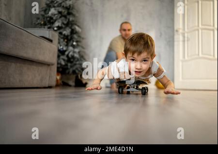 Padre con figlio che gioca sullo skateboard a casa Foto Stock