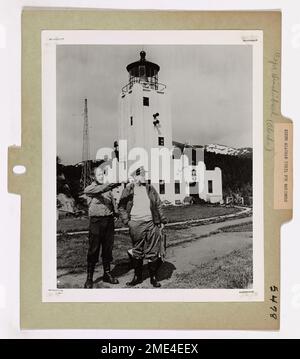 Mantiene la veglia dell'Alaska per i marinai (2 di 7). A sinistra in questa fotografia è Arie Van Der Meet, Jr., compagno di boatswain seconda classe, di Seattle, Washington, che è responsabile degli Stati Uniti Stazione della Guardia Costiera leggera a Cape Hinchinbrook, Alaska. Dopo un giro di un anno di servizio come guardiano della luce, sarà ruotato di nuovo negli Stati Uniti. Qui sta indicando le attrazioni alla stazione al comandante James S. Muzzy, anche di Seattle, ufficiale esecutivo del NORTHWIND, durante la visita di rifornimento della nave a Hinchinbrook. Dietro di loro si trova la stazione, situata sul lato est dell'entrata di Hinchinbrook al Principe Foto Stock