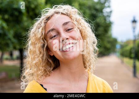 Felice giovane donna con capelli biondi nel parco Foto Stock