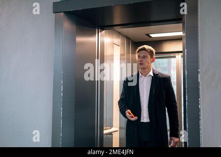 Uomo d'affari che esce dall'ascensore alla stazione Foto Stock