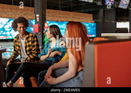 Uomo felice che parla con le donne al bowling Foto Stock