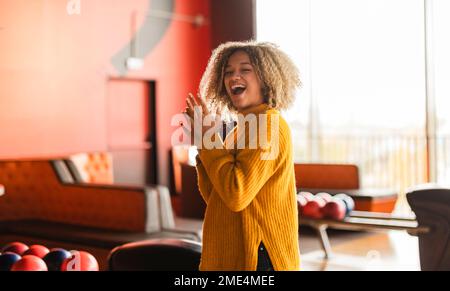 Allegra giovane donna che batte al bowling Foto Stock