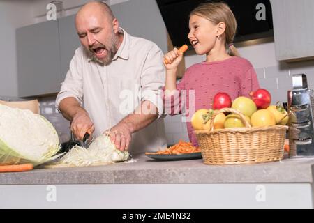 Padre e figlia preparano un pasto sano e si divertono in cucina a casa Foto Stock