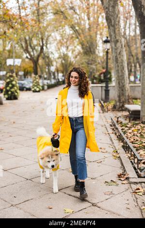 Giovane donna sorridente che cammina con il cane sul sentiero Foto Stock