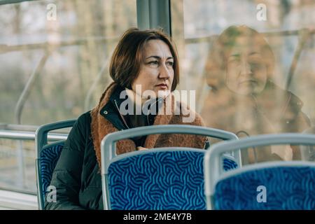 Donna matura e premurosa seduta in tram Foto Stock