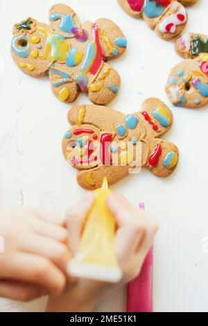 Mani di ragazzo decorazione biscotti di pan di zenzero sul tavolo Foto Stock