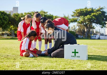 Sport, primo soccorso e squadre di calcio per bambini con un infortunio dopo una partita in una huddle aiutare una ragazza atleta. Fitness, allenamento e bambino con un dolore, dolore Foto Stock