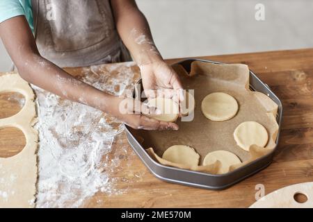 Primo piano di bambina che cuoce pasta fatta in casa e torta in cucina e tenendo pasta, spazio copia Foto Stock