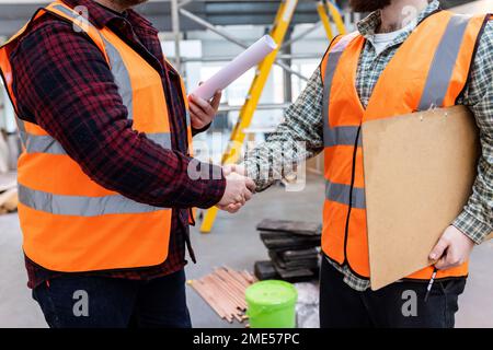 Gli ingegneri scuotono le mani l'uno con l'altro in cantiere Foto Stock