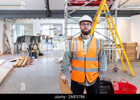 Giovane ingegnere che tiene la clipboard in piedi in cantiere Foto Stock