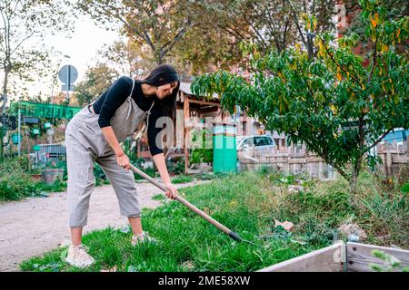 Donna felice giardinaggio con pala in giardino urbano Foto Stock
