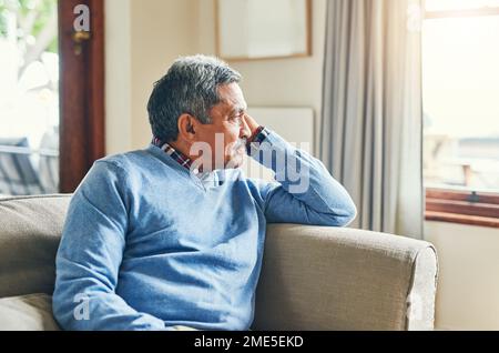 Chi avrebbe pensato Id farlo fino a questo punto. un uomo anziano che guarda molto premuroso mentre si rilassa su un divano a casa. Foto Stock