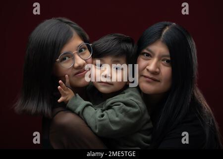 madre messicana che abbraccia e sorride con canzone e figlia Foto Stock