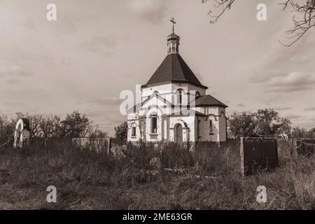 Campagna. Chiesa ortodossa danneggiata dal bombardamento. Buchi da proiettili e shrapnel nella recinzione. Guerra in Ucraina. Invasione russa dell'Ucraina Foto Stock