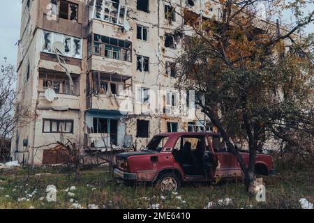 Guerra in Ucraina. Auto civile distrutta si trova vicino a una casa distrutta. Sul corpo della vettura ci sono buchi da proiettili e shrapnel Foto Stock