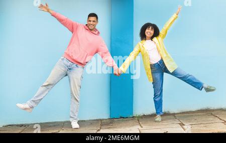 Felice, sorridere e felice coppia che tiene le mani nella strada della città facendo una posa sciocca, divertente e goofy. Felicità, amore e giovane uomo e donna con Foto Stock