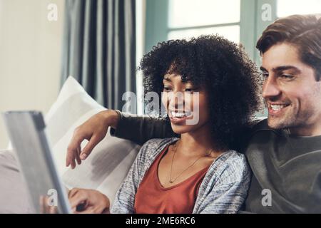 I giorni trascorsi insieme sono sempre speciali. una giovane coppia affettuosa che utilizza un tablet digitale insieme e che trascorre un po' di tempo di qualità insieme a casa Foto Stock