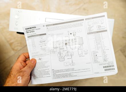 Parigi, Francia - 18 ottobre 2023: POV carta da mano maschio con guida rapida modalità di collegamento manuale di Onkyo BD-SP809 top-of-range Blu-ray deck Foto Stock