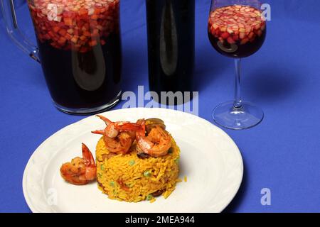 Riso paella preparato con gamberi, zafferano, pollo, frutti di mare e verdure, piatto tradizionale di Valencia Spagna accompagnato da una brocca di clericot Foto Stock