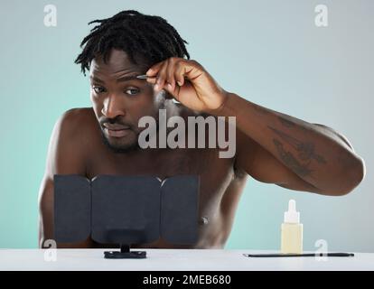 Back man, pinzette e sopracciglia in studio con viso, specchio e bellezza per la cura del corpo su sfondo blu. Modello, cosmetici e rimozione dei peli del viso a. Foto Stock