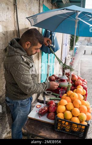 Scena di strada con l'uomo che prepara succo di melograna a Betlehem, Israele, Asia. Foto Stock