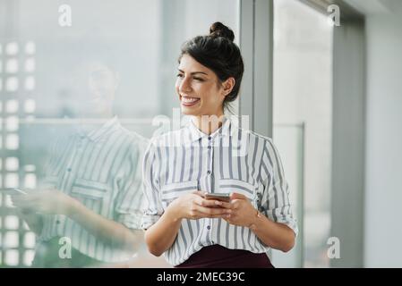 Non si può porre fine a una mente ambiziosa. una giovane donna d'affari sicura che usa un cellulare in un ufficio. Foto Stock