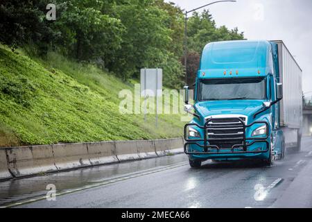 Cabina alta per impieghi industriali potente carro di trasporto lungo classico smeraldo grande semirimorchio che trasporta carichi commerciali in un semirimorchio per furgoni asciutti che guida su Foto Stock