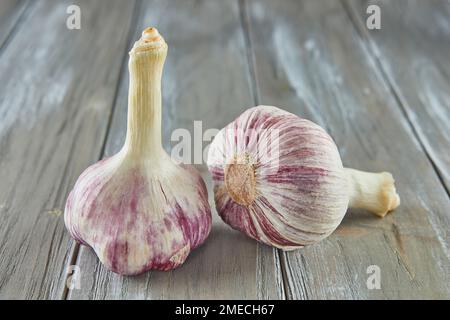 Bulbi freschi di aglio impilati su fondo grigio di legno Foto Stock