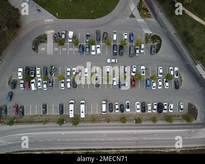 Ampio e affollato parcheggio moderno con strade simmetriche file di piazzole di parcheggio molto simmetriche e colori vista aerea dal drone in alto guardando in basso. Foto Stock