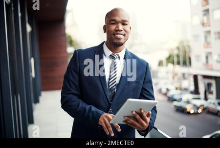 Solo un uomo moderno con il suo strumento moderno preferito. Ritratto di un bel giovane uomo d'affari che usa un tablet digitale fuori dal suo ufficio. Foto Stock