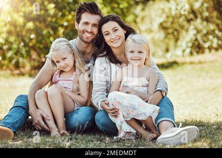 Famiglia, giardino e ritratto di genitori, bambini e persone felici sul prato del parco al sole. I bambini, la mamma ed il papà sorridono con amore nella natura, nella vacanza e. Foto Stock