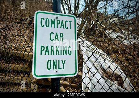 Un primo piano del cartello "solo parcheggio per auto compatte" su una recinzione a rete Foto Stock