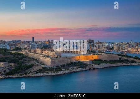 Valletta, Malta - Vista panoramica Fort Manoel e Sliema presi da la Valletta con un colorato tramonto rosso e cielo blu Foto Stock