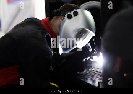 Operatore industriale nella saldatura a casco di pezzi in acciaio. Messa a fuoco selettiva. Foto Stock