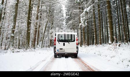 Camper Van guida su una strada attraverso una foresta coperta di neve in inverno, vacanza avventura e stile di vita nei boschi, Germania Foto Stock