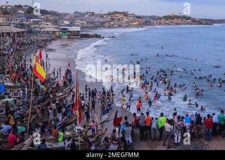 Costa del Capo, Ghana - 05 aprile 2022: Costa dell'Oceano Atlantico con le barche e la gente africana locale del Ghana Foto Stock