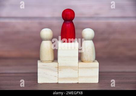 Concetto vincente - figura rossa al centro di un'altra figura su blocchi di legno. Foto Stock