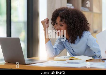 Una donna d'affari nera che lavora su un notebook si sente euforica vincita. Excited femmina trionfo ottenere buone notizie dal lavoro Foto Stock