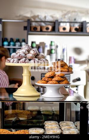 La giovane barista ragazza vicino a una moderna finestra gode di una tazza di caffè, guardando fuori, Buongiorno, giornata di lavoro, libero dal lavoro e dai doveri. Foto Stock