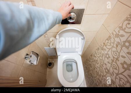 Mano di uomo premere a filo wc con due pulsanti separati. Foto Stock