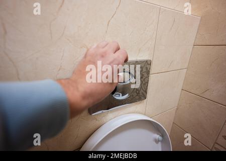 Mano di uomo premere a filo wc con due pulsanti separati. Foto Stock