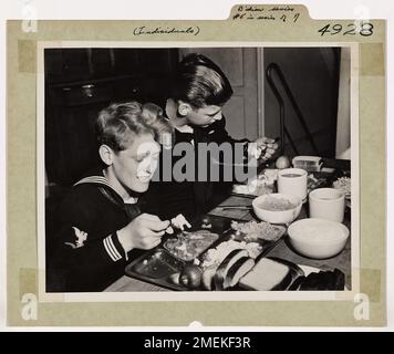 Il ragazzo di mistero del fronte d'acqua tedesco (No. 5 in Una serie di 7 foto). Chow Down - Un uomo di servizio è un mangiatore sostanzioso, per i motivi migliori. Durante il giorno si è fatto un appetito. Dopo una dura giornata di lavoro a bordo della taglierina della Guardia Costiera EAGLE, Eddie sa cosa fare con il chow serale. Può ricordare i giorni in cui i tedeschi superavano la Francia e i mesi dei suoi viaggi e delle sue razioni di scarti. Foto Stock