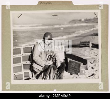 Coast Guardsman trova un momento di riposo. Il fotografo di combattimento della Guardia Costiera William Forsythe, ex fotografo del giornale Washington D.C., riposa per un secondo sulla spiaggia di Gela, Sicilia, prima di tornare alla sua nave. Coast Guardsman Forsythe fu tra i primi ad atterrare sulla spiaggia con l'esercito. Foto Stock