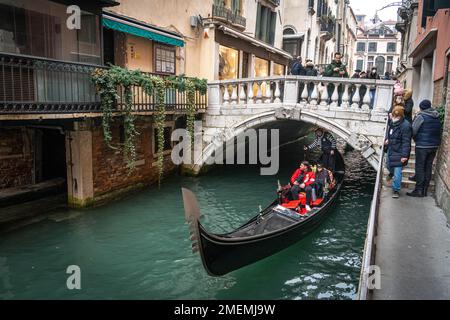 La gondola scorre sotto il ponte nello stretto canale di Venezia, in inverno Foto Stock