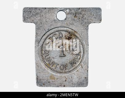 Un vecchio gettone di latte sporco e macinato su sfondo bianco. La superficie è molto graffiata e sporca. Il gettone è realizzato in metallo. Foto Stock
