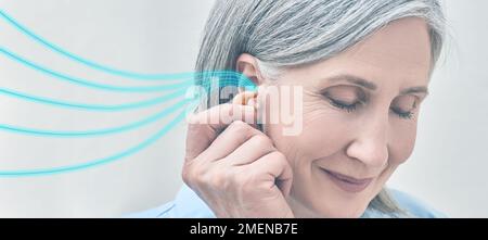 Donna matura che tiene l'apparecchio acustico vicino all'orecchio con onde sonore colorate che mostrano una varietà di suoni che vanno all'orecchio. Apparecchi acustici Foto Stock