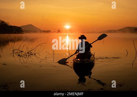 Donne in kayak file nel serbatoio durante l'alba, Harirak parco forestale Huai Nam Man Reservoir Loei Thailandia 21 gennaio 2023 Foto Stock