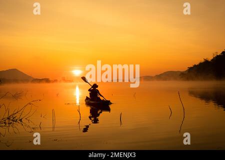 Donne in kayak file nel serbatoio durante l'alba, Harirak parco forestale Huai Nam Man Reservoir Loei Thailandia 21 gennaio 2023 Foto Stock