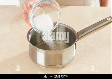 Preparare la torta alla polenta al limone, mettere il succo di limone e lo zucchero in padella Foto Stock