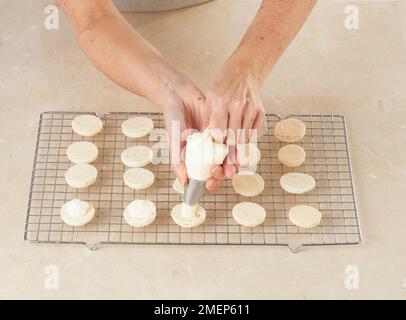 Preparazione di amaretti di fragola e crema, aggiunta di un composto cremoso sui amaretti Foto Stock